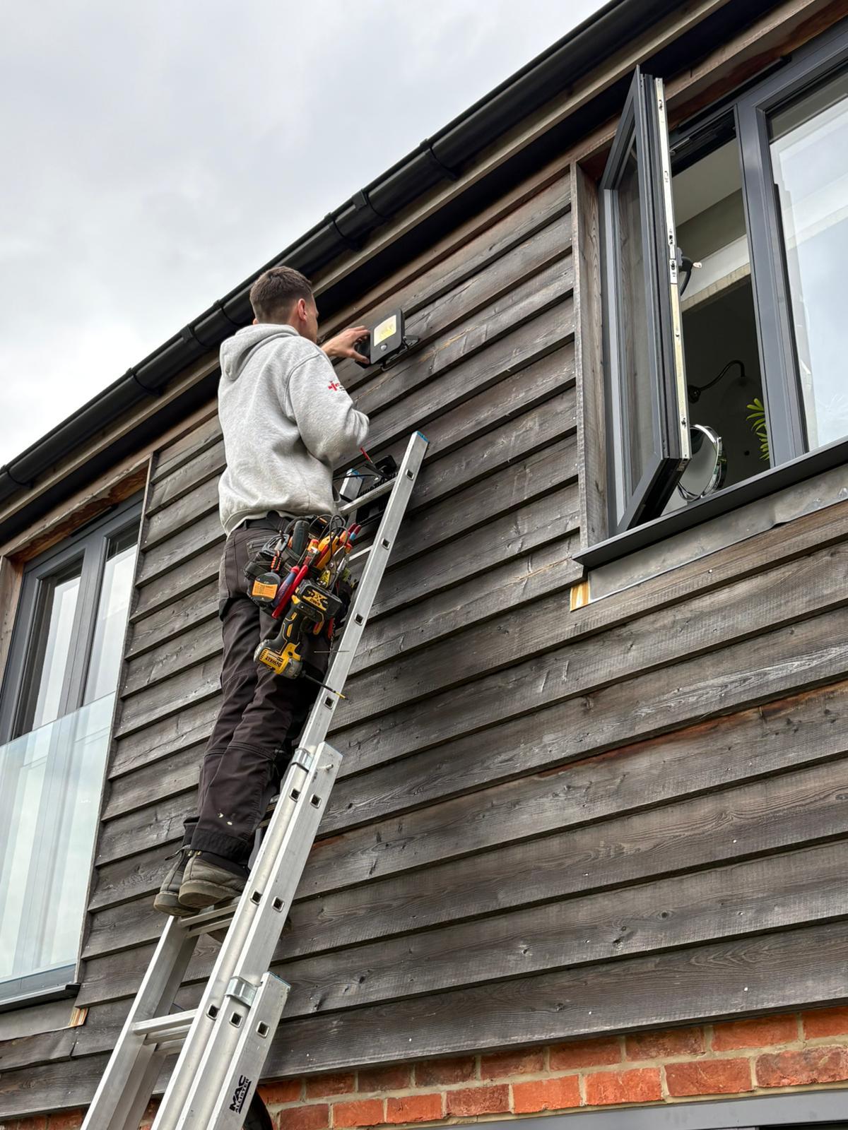 Harry on a ladder installing a security light